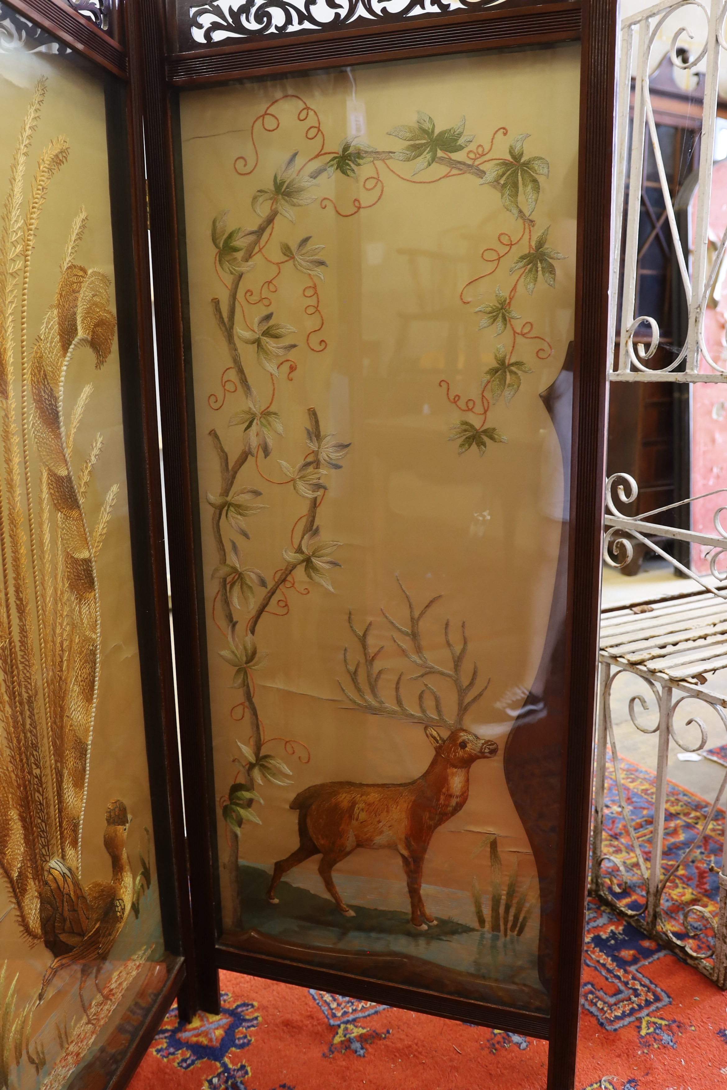 An Edwardian silk thread embroidered two fold dressing screen worked with a peacock and a stag, each panel width 57cm, height 152cm